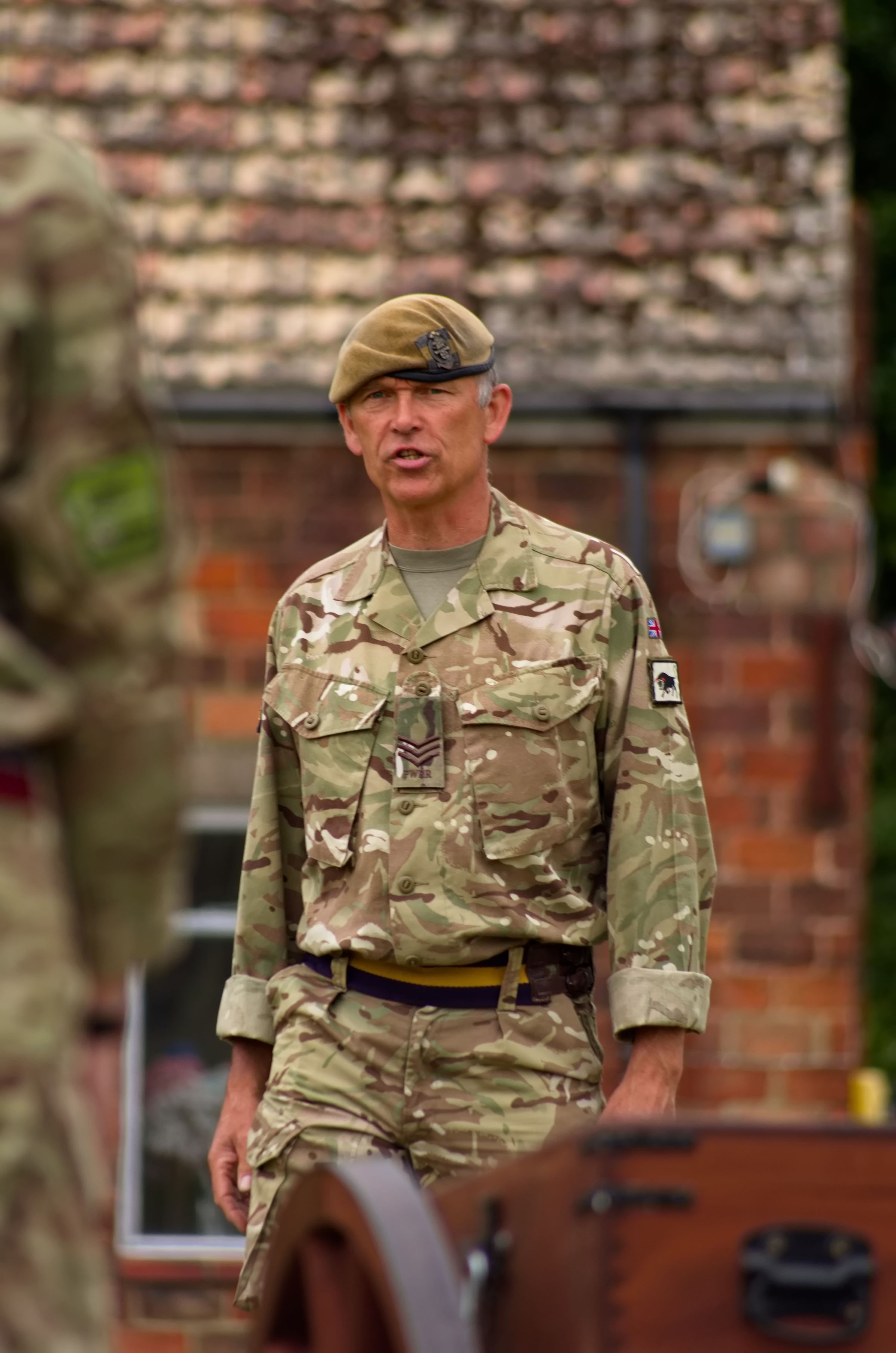 A British Army Sergeant in front of a wooden gun.