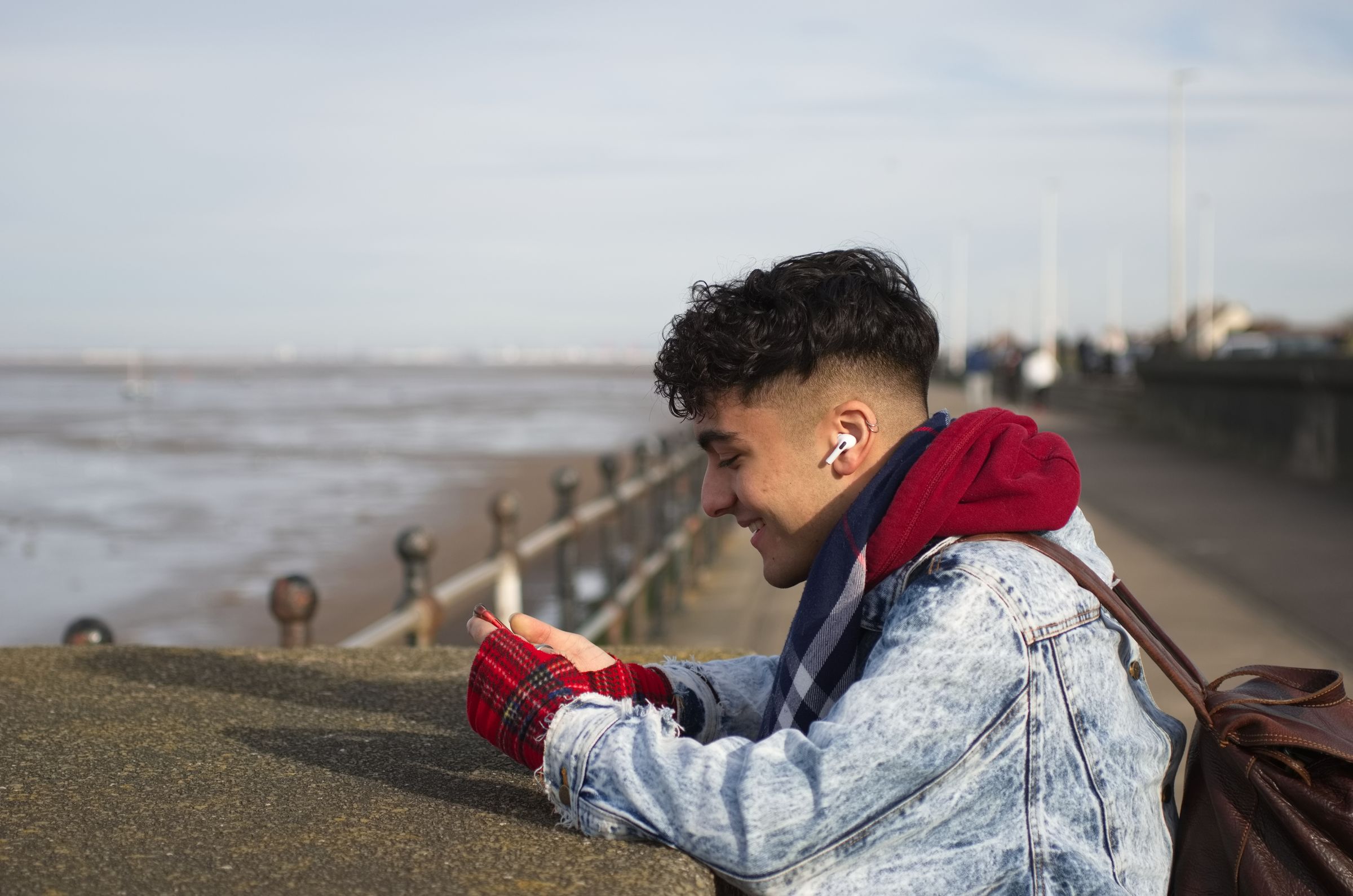 A man looking at his phone on a beach promenade.