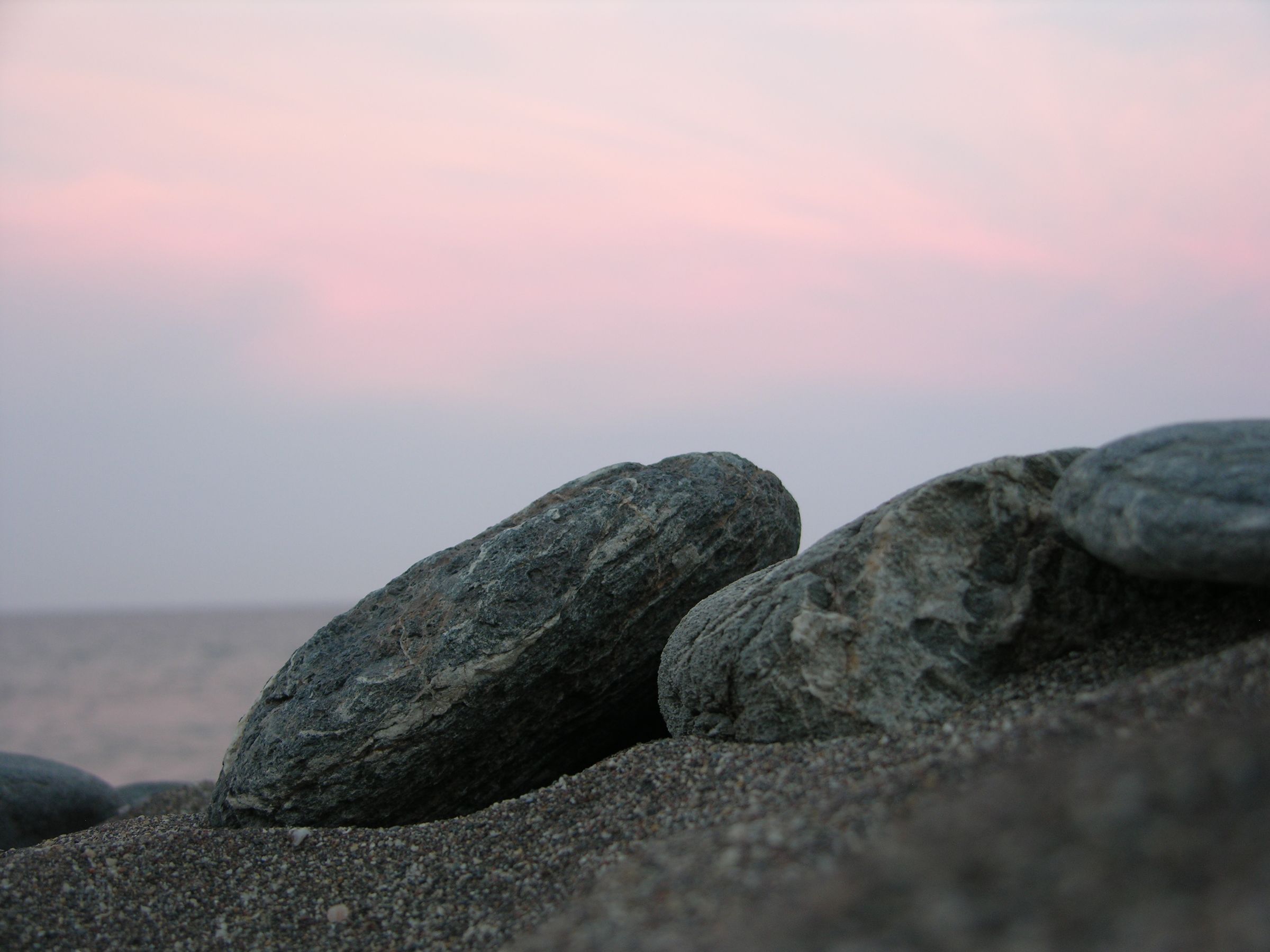 A collection of stones on a beach at sunset.