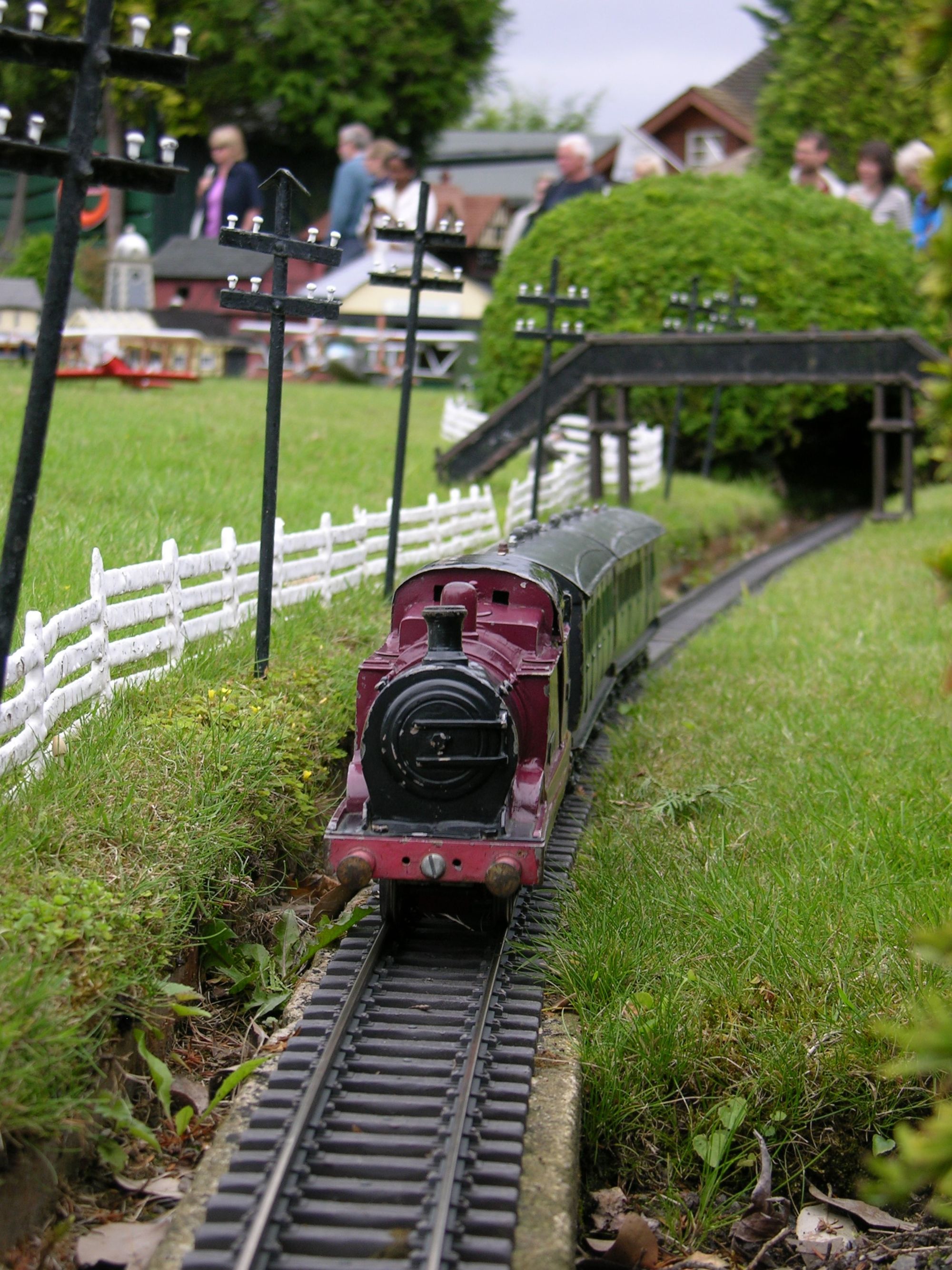 A maroon model train in a model village.