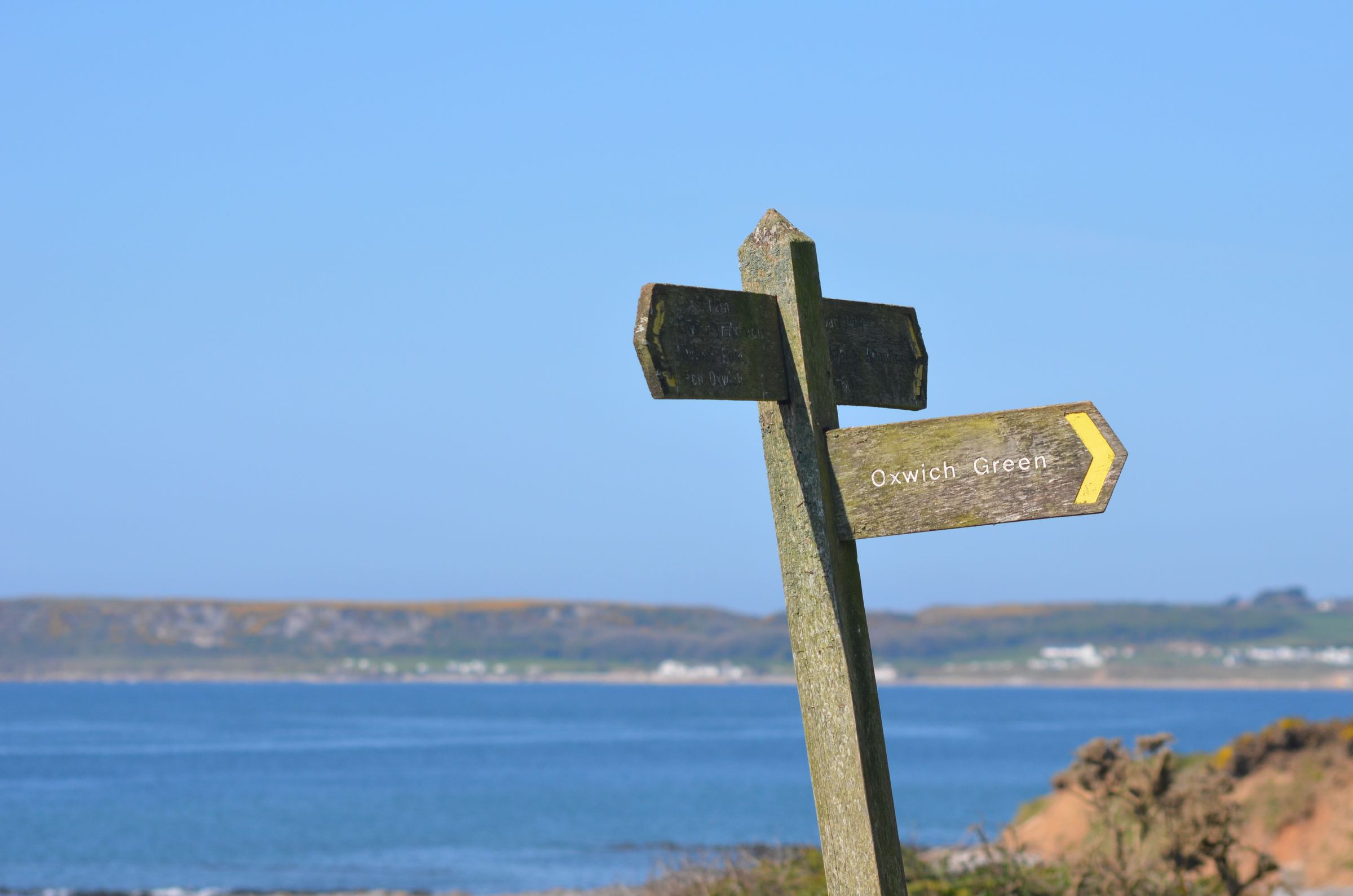 A sign on a cliff overlooking the sea.