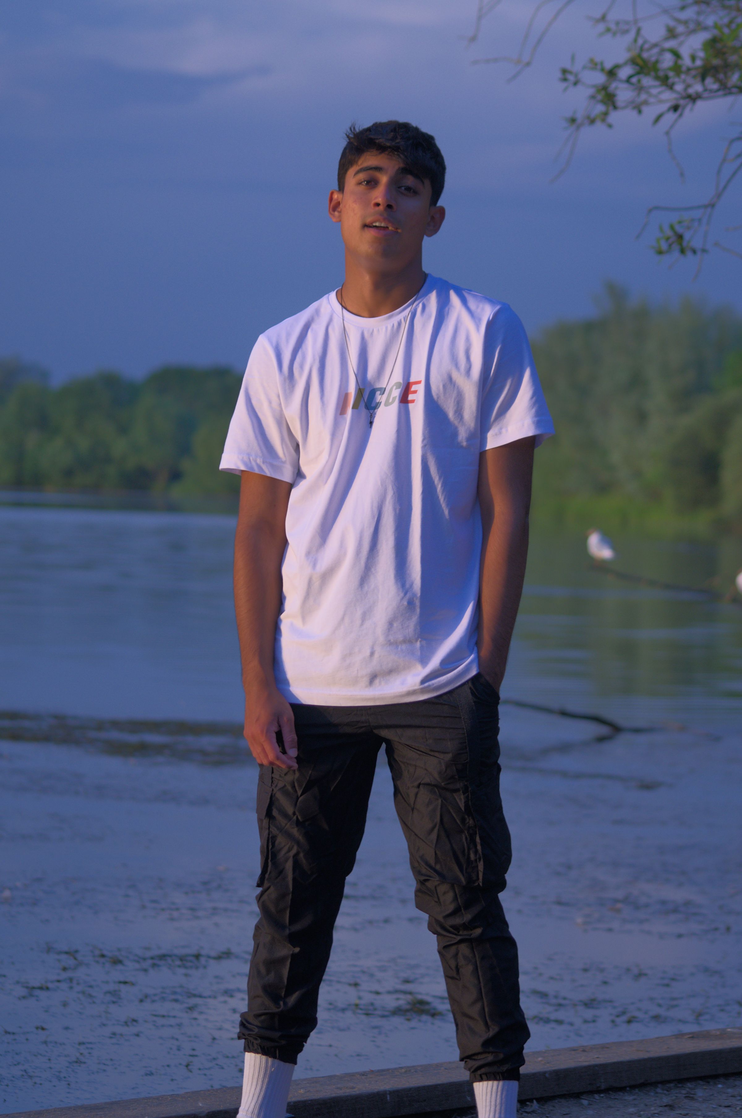 A man standing in front of a lake and looking at the camera.