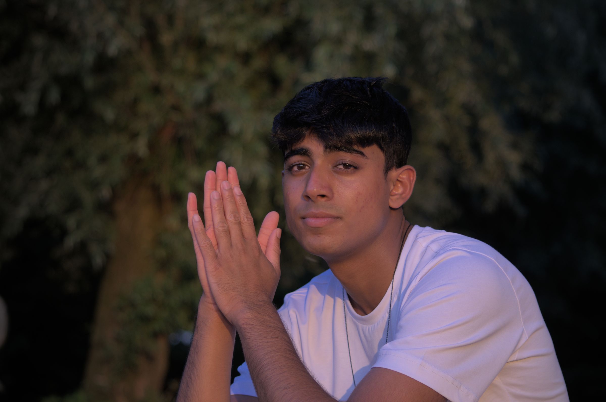 A man staring into the distance at sunset and holding his hands in front of him.