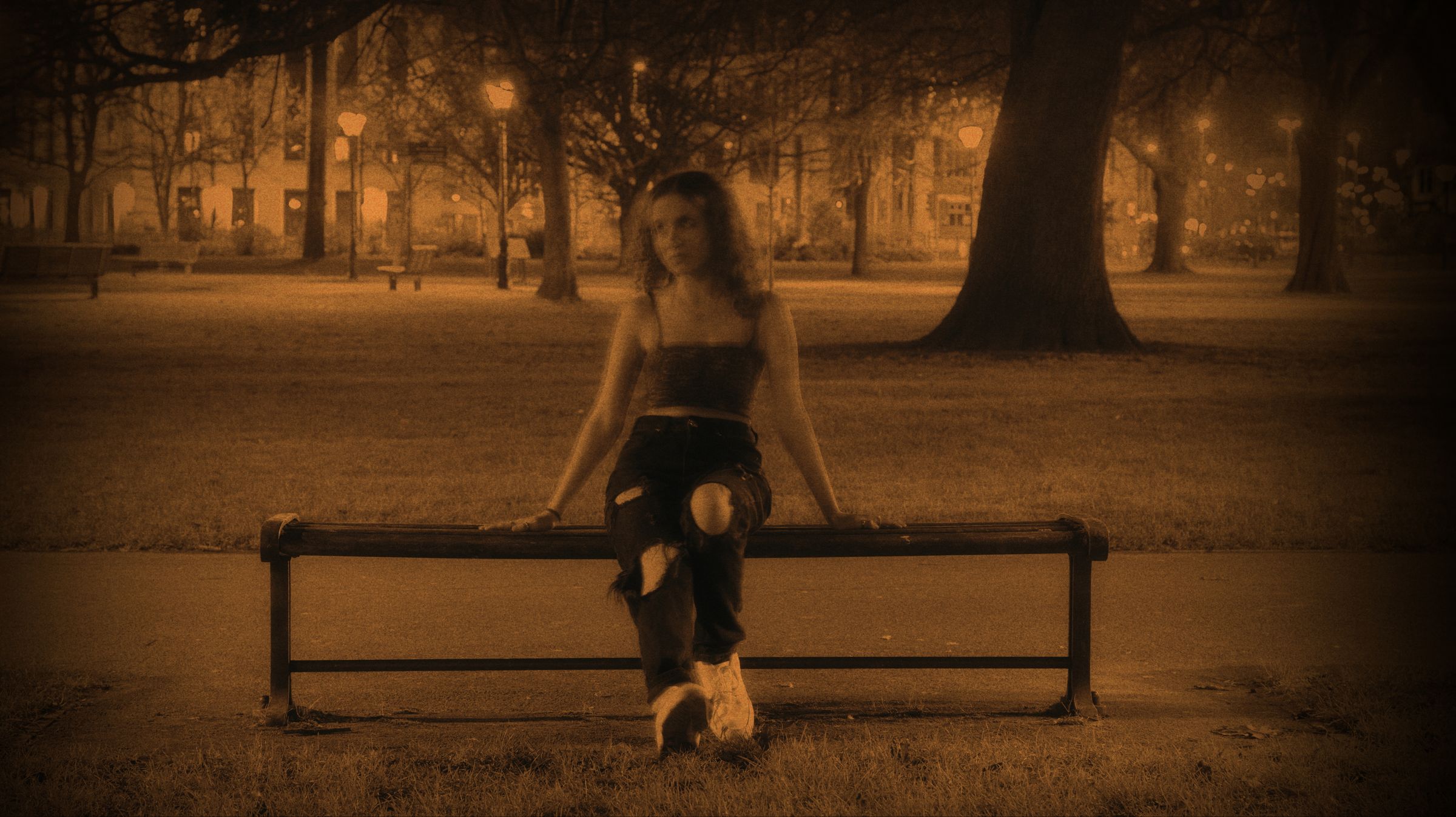 Pop artist cover photo. A woman sat on a bench at night, tinted orange.